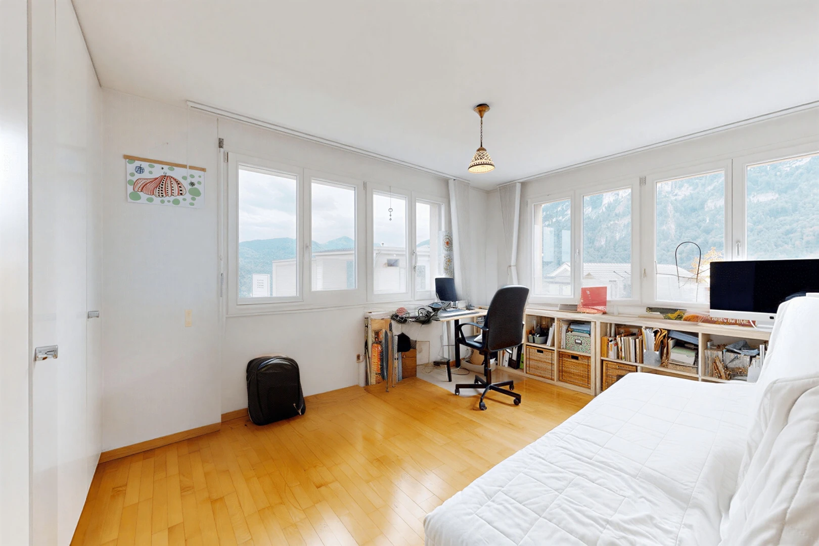 room / bedroom featuring an office area, pendant lighting, and light wood-style floors