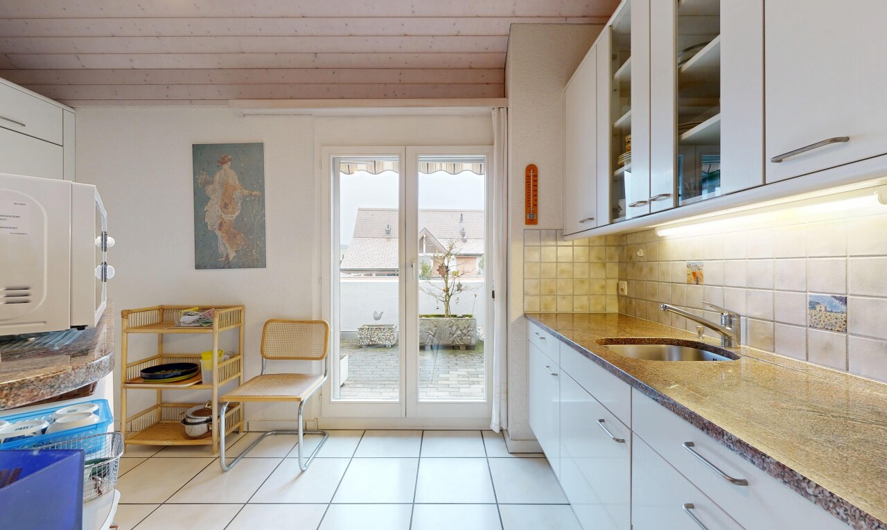 cuisine avec armoires blanches, white cabinets, plans de travail en pierre, stone countertops, et lumière naturelle