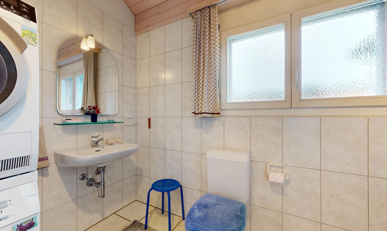 salle de bains avec miroir, toilette, tile wall, mur en carrelage, et natural light