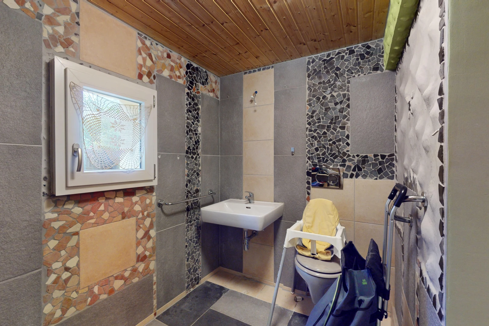 salle de bains avec mur carrelé, vasque, toilettes, et plafond de bois
