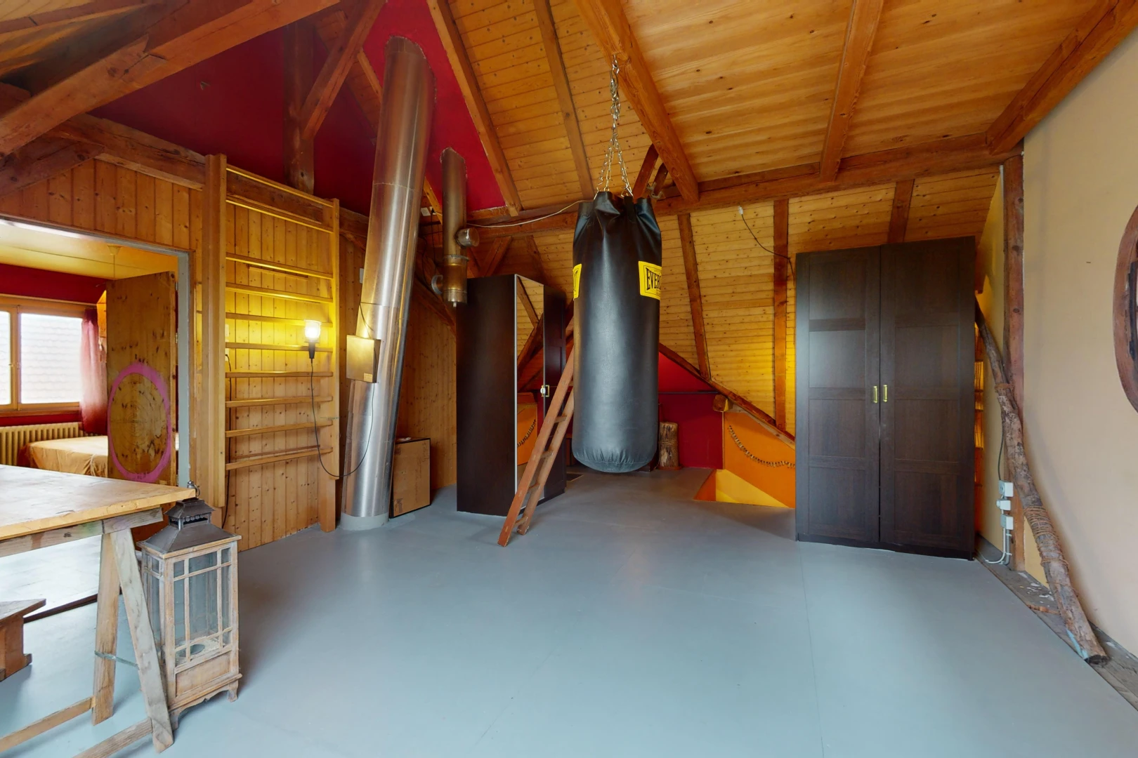 chambre avec poutres apparentes, plafond de bois, plafond voûté, sol en béton, et lumière naturelle