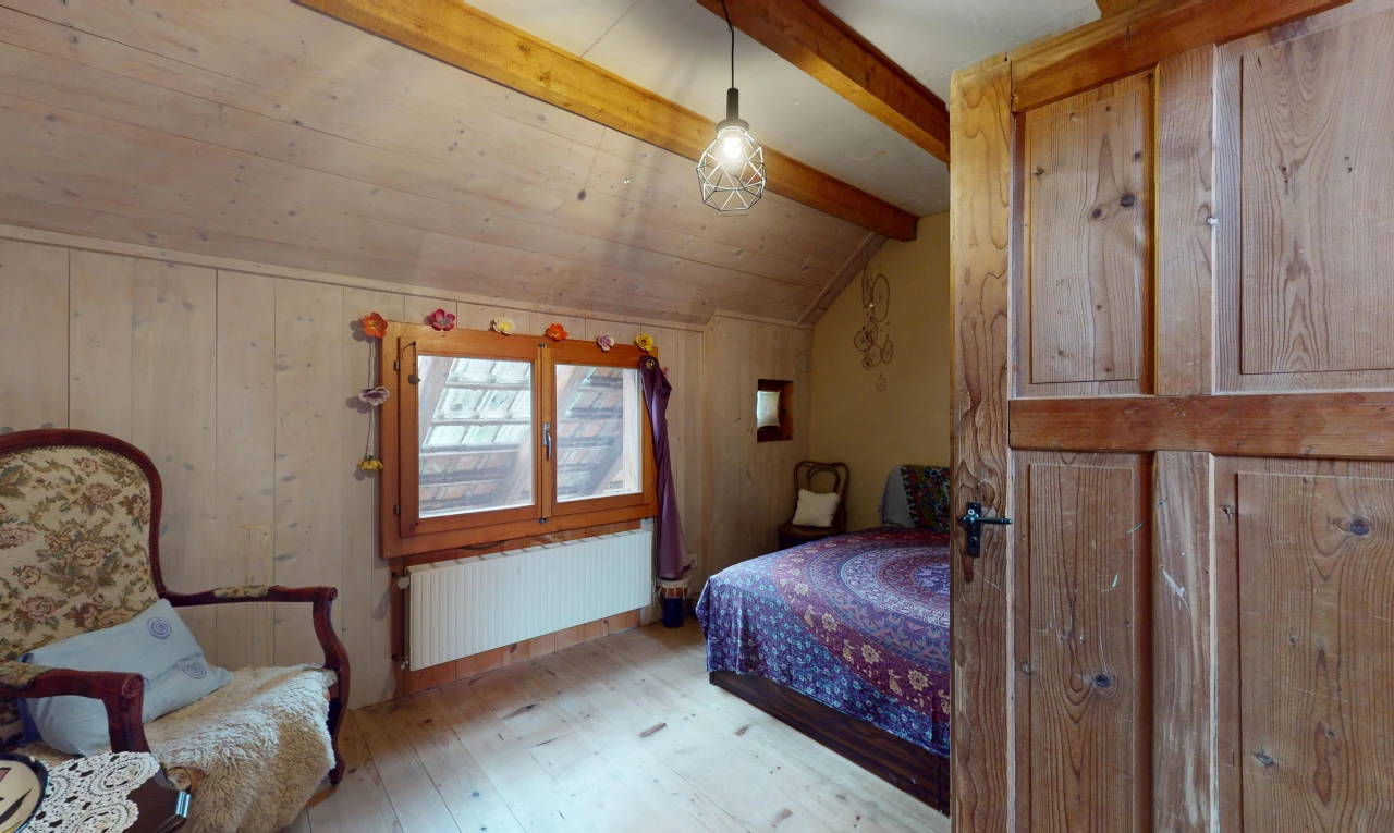 chambre avec plancher de bois, poutres apparentes, lumière naturelle, plafond voûté, et radiateur