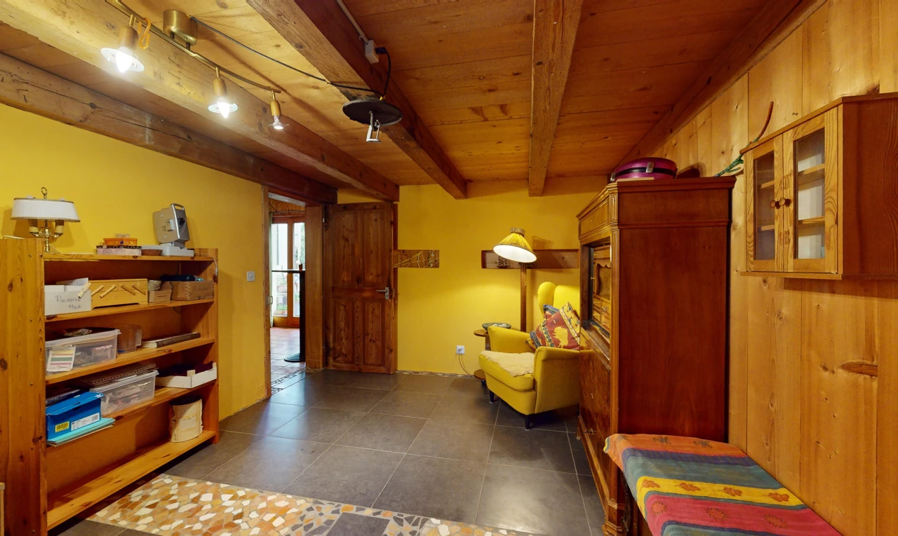 espace intérieur avec plafond de bois, poutres apparentes, mur en bois, lumière naturelle, et éclairage sur rail