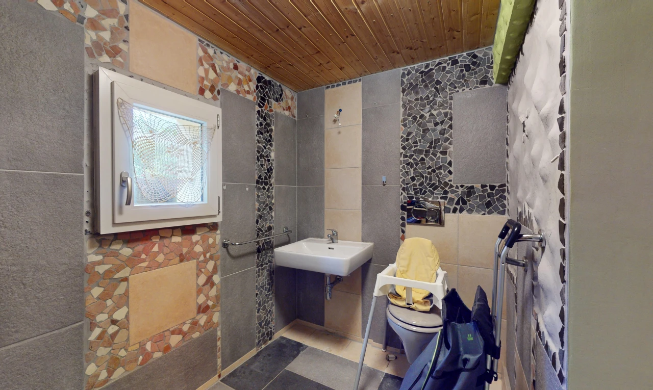 salle de bains avec mur carrelé, vasque, toilettes, et plafond de bois
