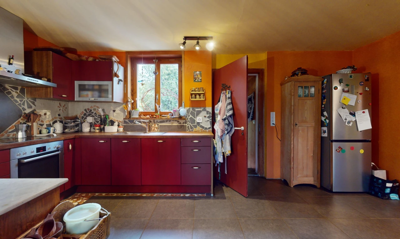 cuisine avec crédence, four, lumière naturelle, meubles rouges, et réfrigérateur