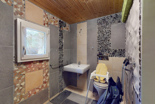 salle de bains avec mur carrelé, vasque, toilettes, et plafond de bois