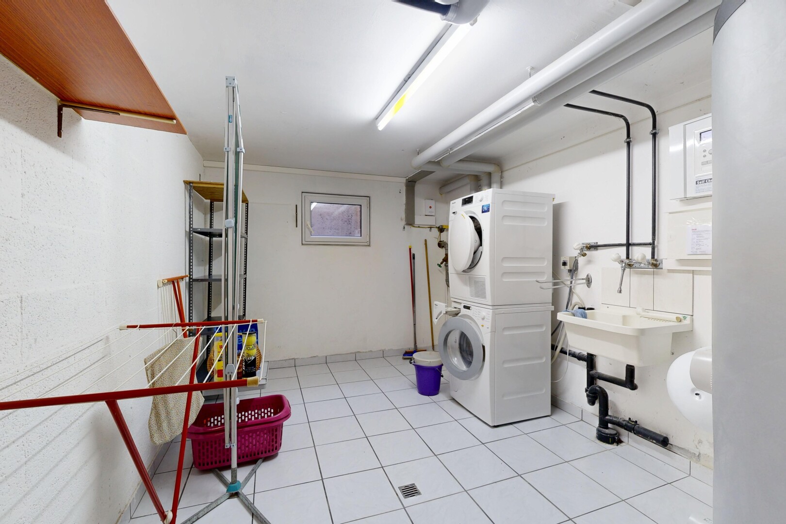 buanderie avec light floor, lave-linge et sèche-linge superposés, inside property, évier, et sol en carrelage