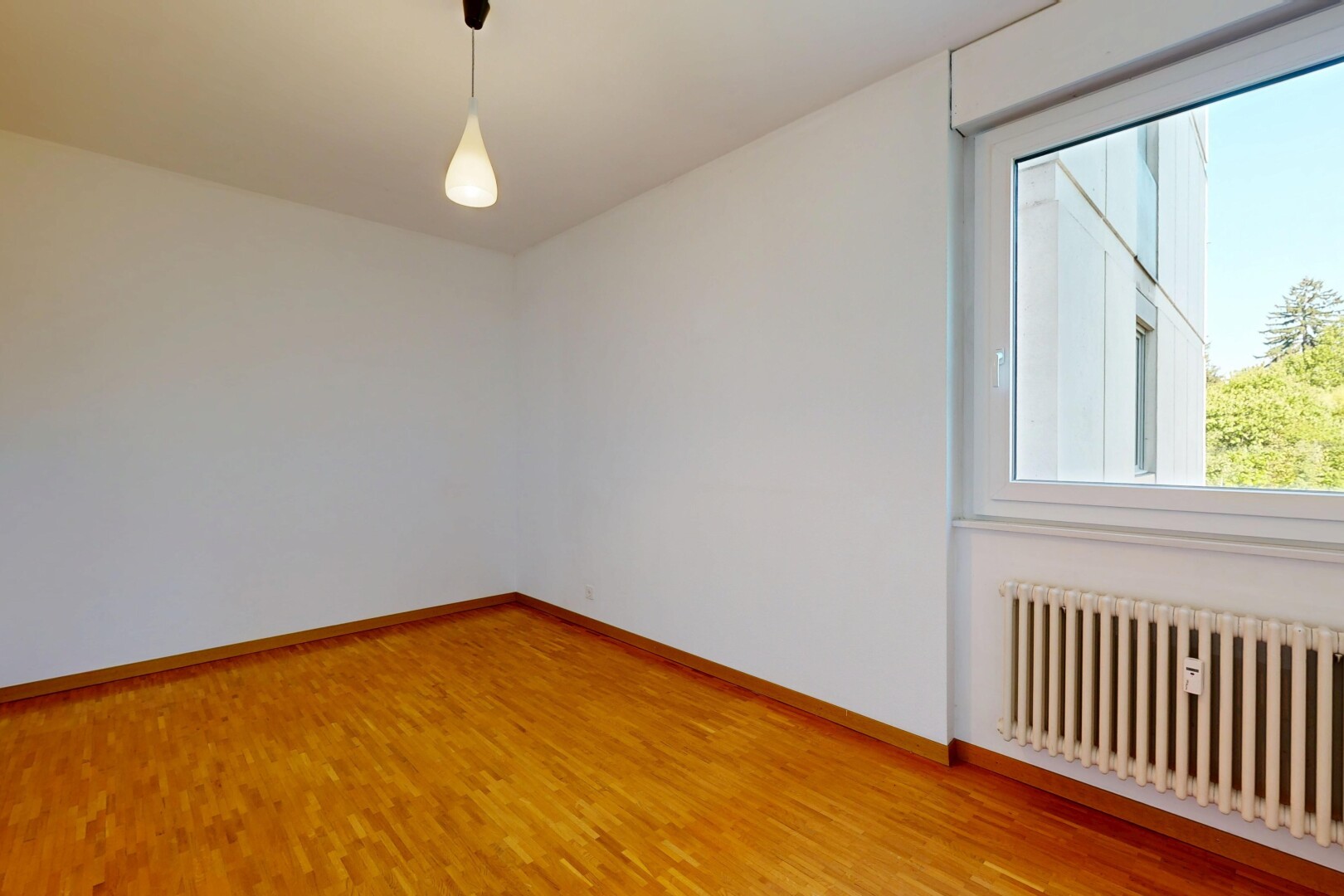 empty room with radiator, decorative light fixtures, and light wood-type flooring