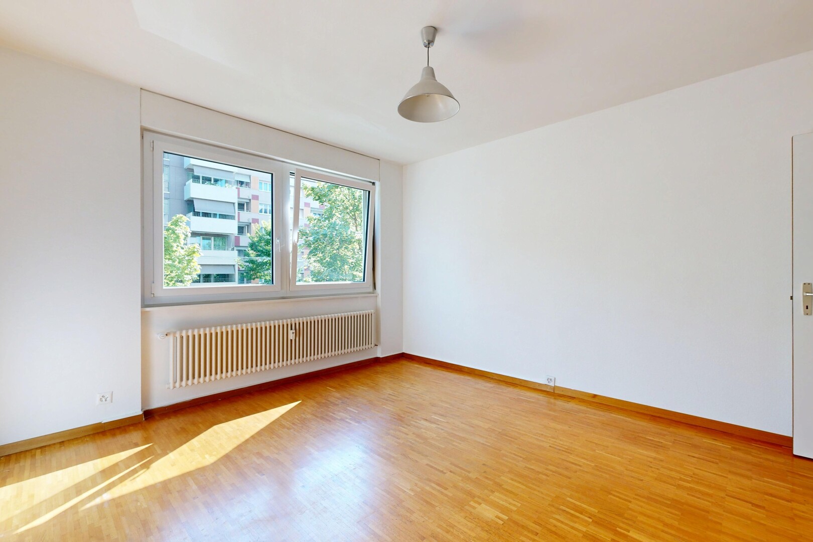 spare room with radiator, decorative light fixtures, and light wood-style floors