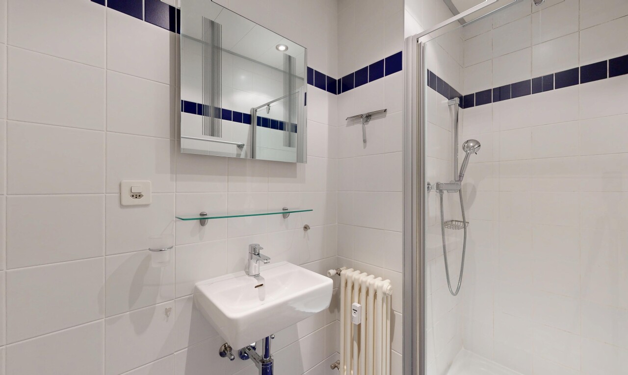 full bathroom featuring radiator heating unit, tile walls, a shower stall, and recessed lighting