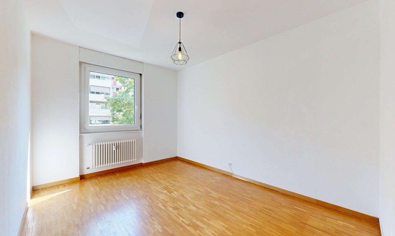 spare room featuring radiator heating unit, light wood-style flooring, and hanging light fixtures