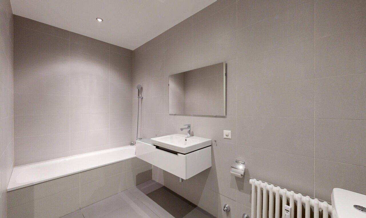 bathroom with tile walls, a relaxing tiled tub, vanity, recessed lighting, and radiator heating unit