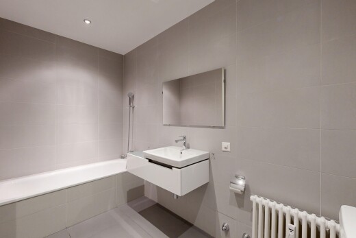 bathroom with tile walls, a relaxing tiled tub, vanity, recessed lighting, and radiator heating unit