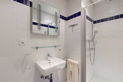 full bathroom featuring radiator heating unit, tile walls, a shower stall, and recessed lighting