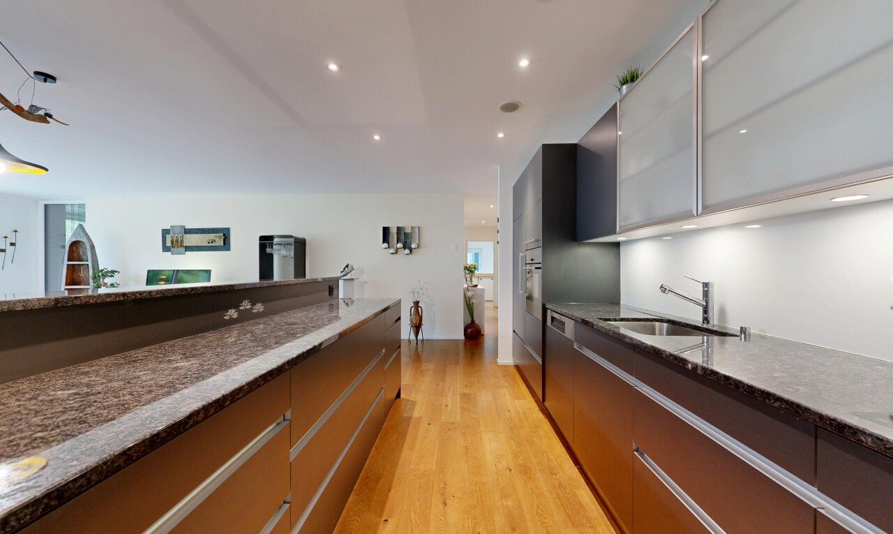 cuisine avec dark countertops, stone countertops, plans de travail en pierre, flat panel cabinets, et armoires à panneau plat