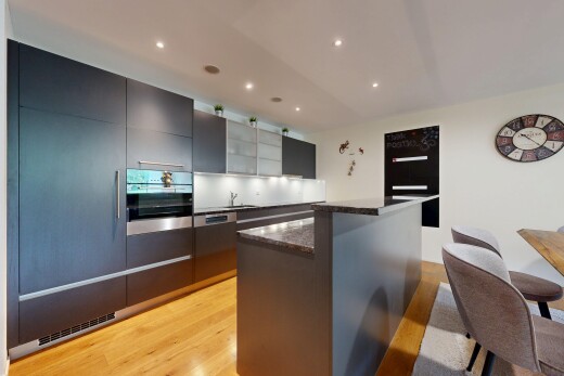 küche mit two heights countertops, dark countertops, light floor, kücheninsel, und kitchen island