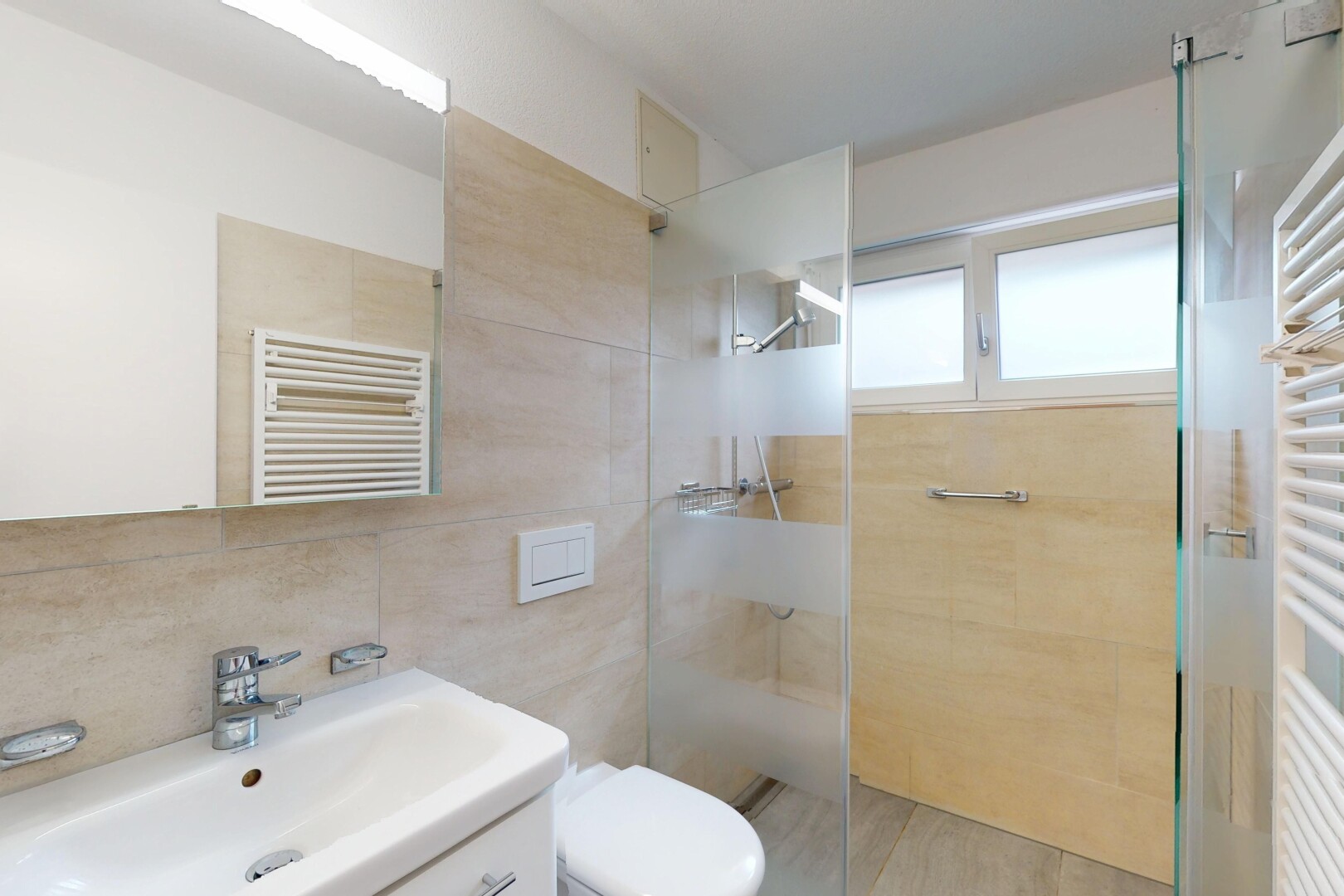 bathroom featuring a towel warmer, radiator, tiled shower, vanity, and tile walls