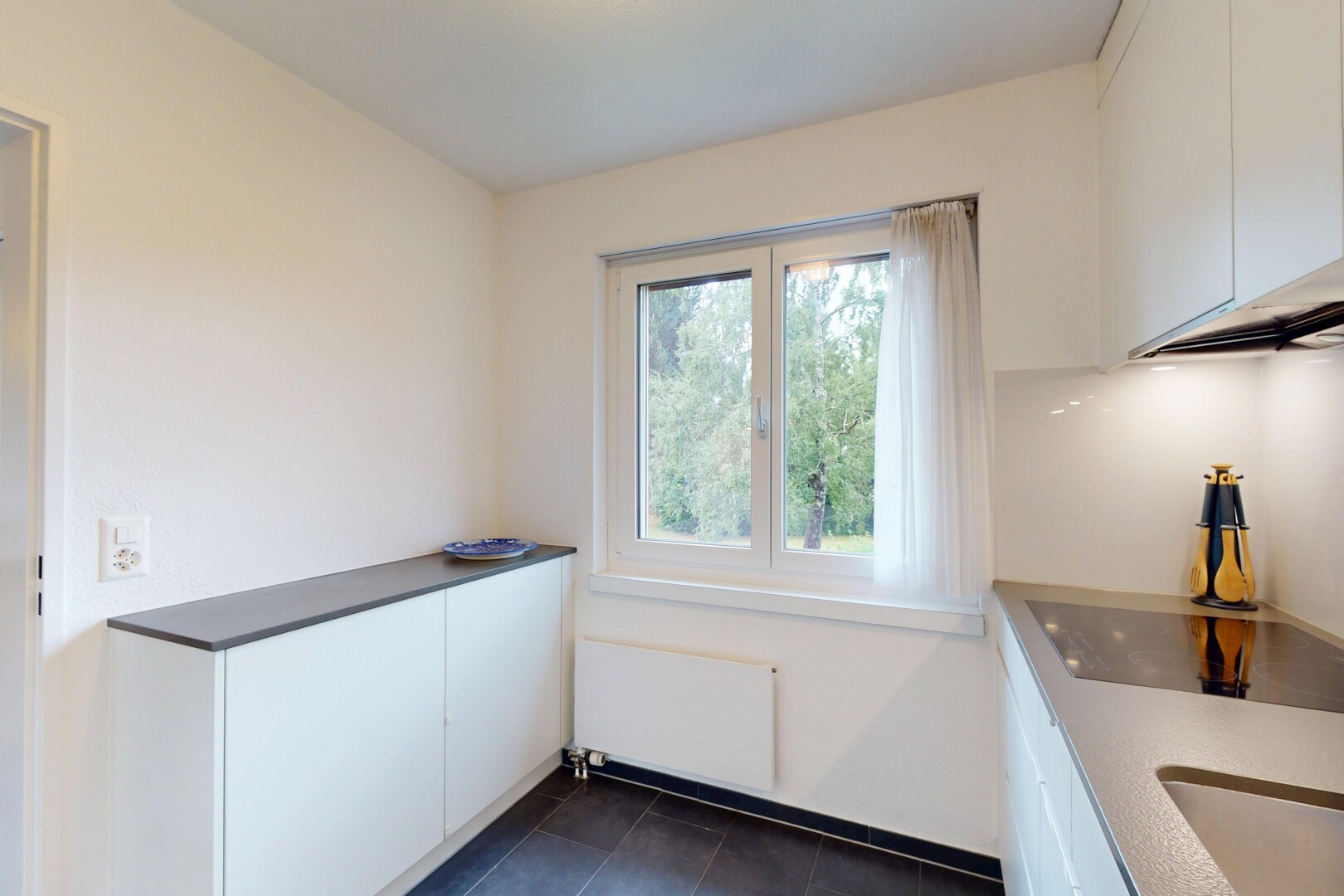 kitchen featuring radiator, white cabinets, black electric stovetop, and dark tile patterned floors