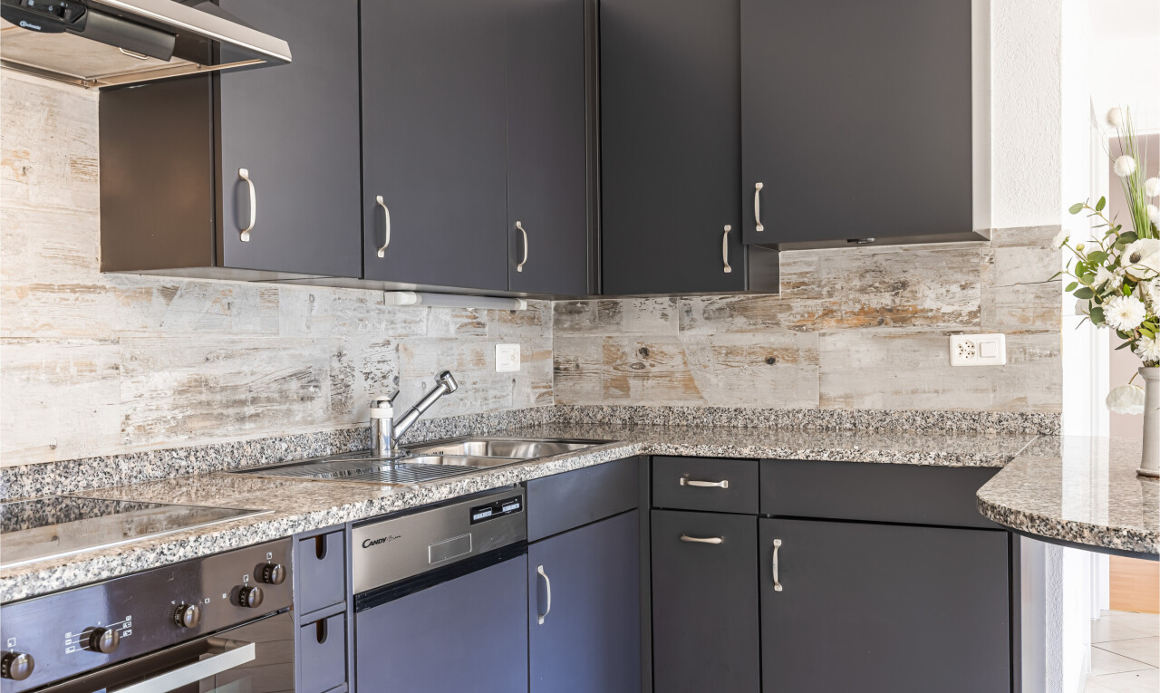 cuisine avec hotte, four, inside property, stone countertops, et plans de travail en pierre