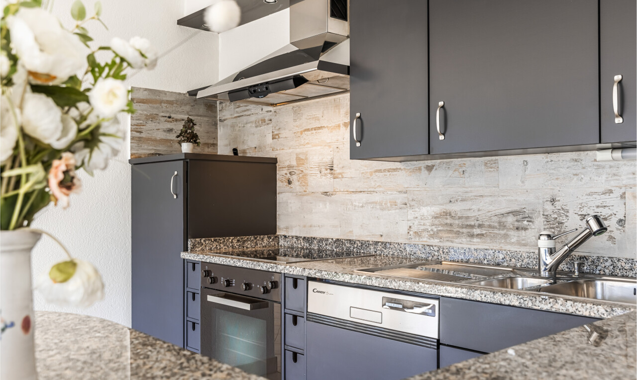 cuisine avec hotte, four, inside property, stone countertops, et plans de travail en pierre