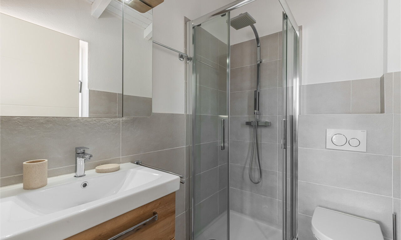 salle de bains avec mur en carrelage, tile wall, lavabo (ou coiffeuse selon le contexte), miroir, et salle de bain complète