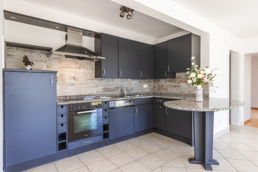 cuisine avec curved countertops, hotte, four, light floor, et backsplash