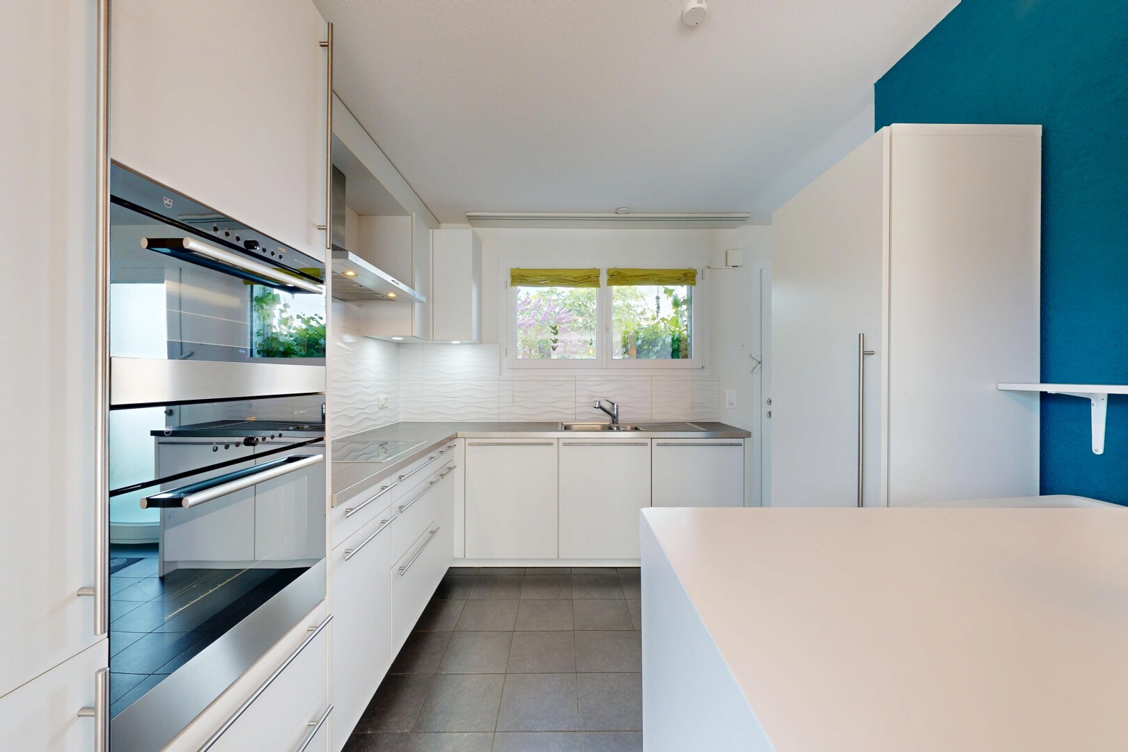 cuisine avec four double, armoires blanches, white cabinets, light countertops, et sol en carrelage