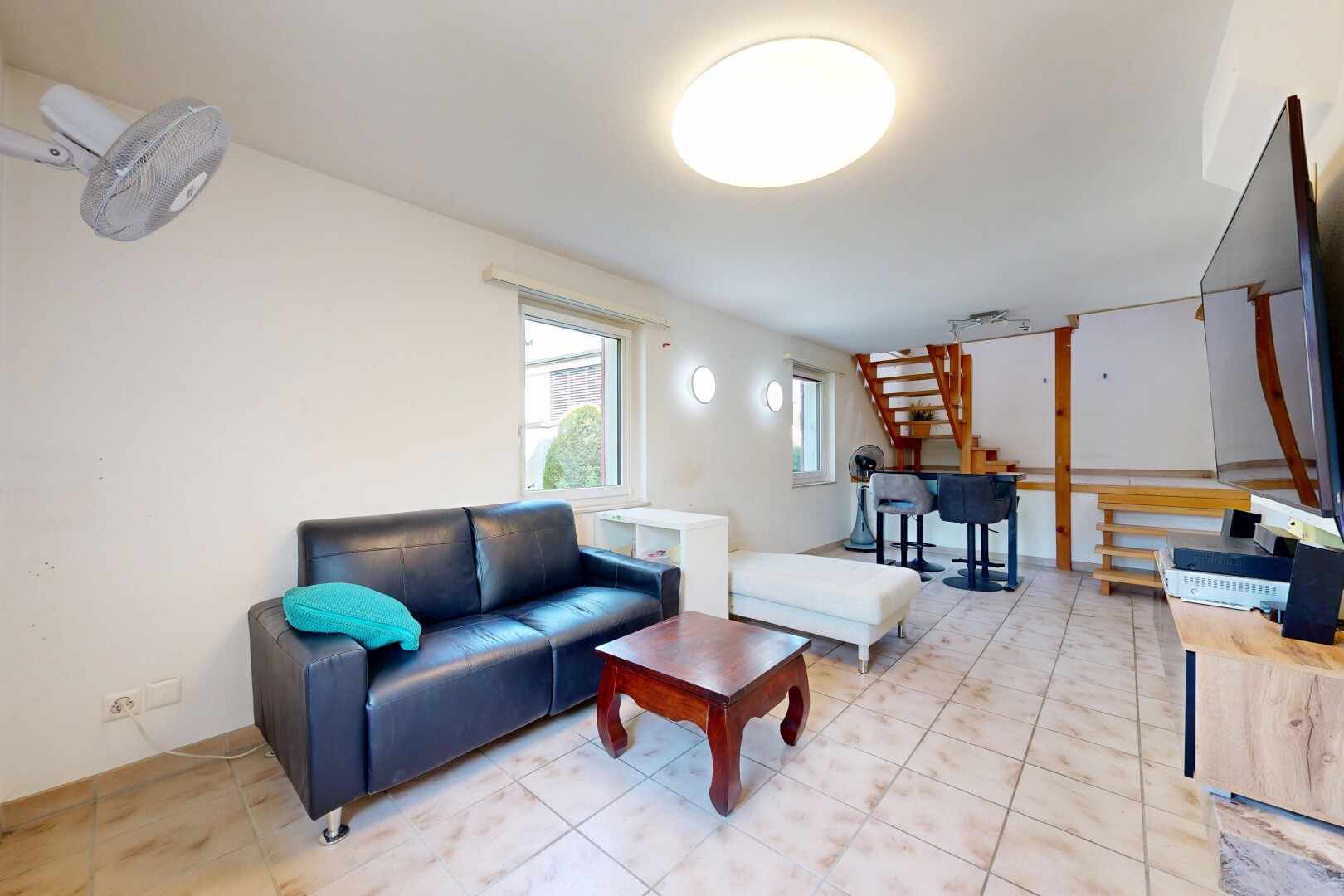 wohnzimmer mit treppen, fernseher, gipskartonwand, drywall, und natürliches licht