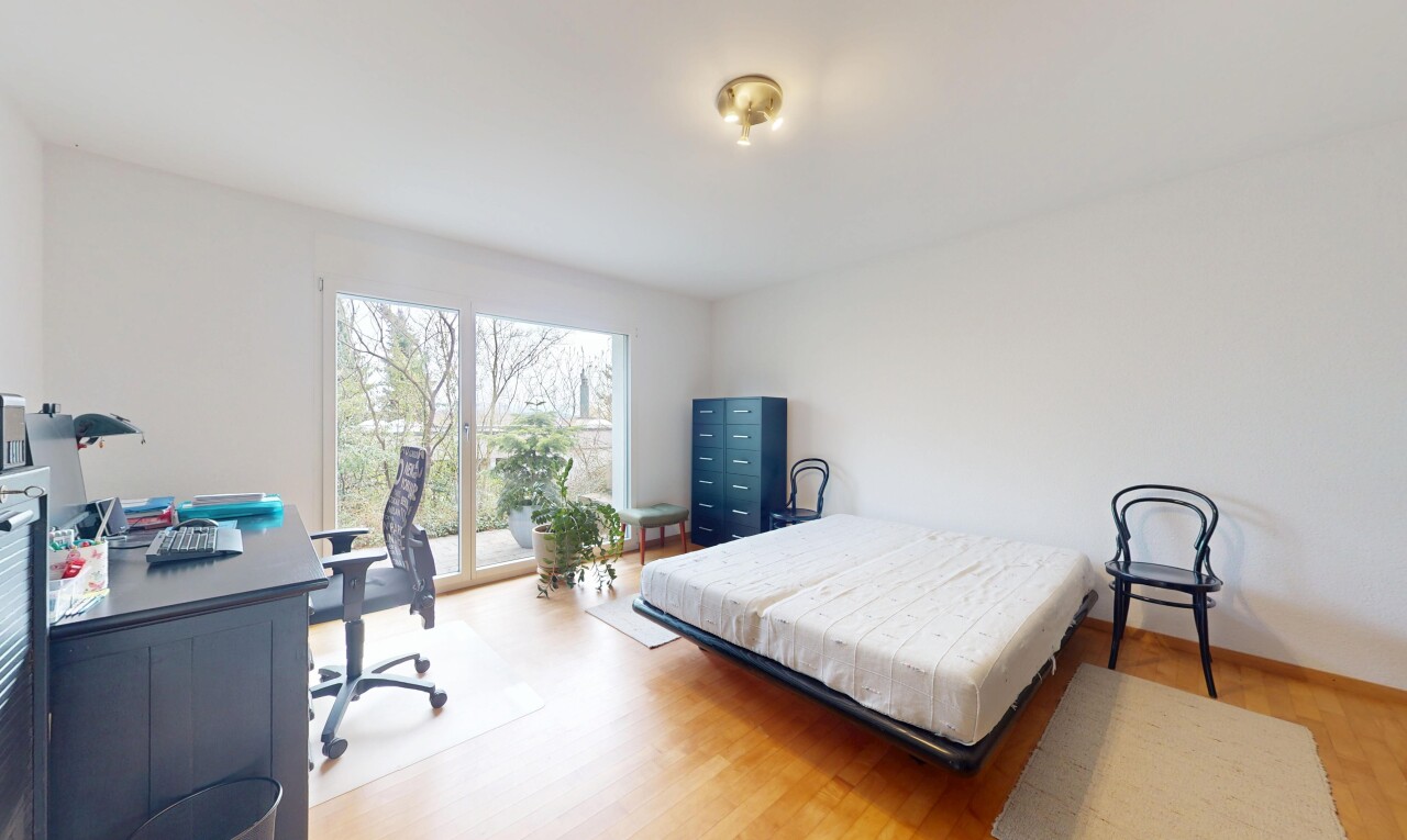 chambre avec sol en finition bois, cloison sèche, espace bureau, plinthes murales, et lumière naturelle