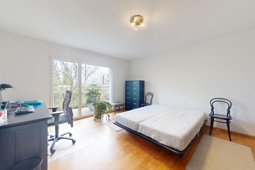 chambre avec sol en finition bois, cloison sèche, espace bureau, plinthes murales, et lumière naturelle