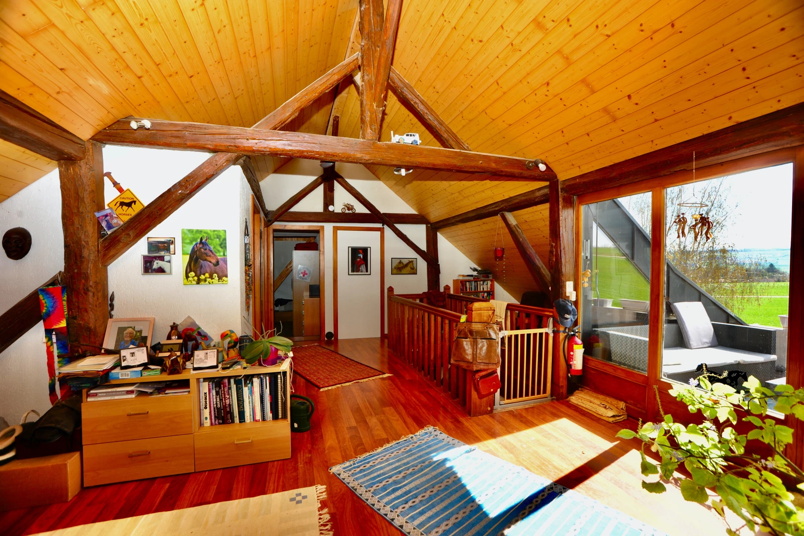 salon avec plancher de bois, plafond voûté, plafond de bois, lumière naturelle, et poutres apparentes