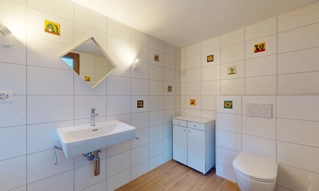 salle de bain avec mur carrelé, miroir, vasque, plancher de bois, et toilettes
