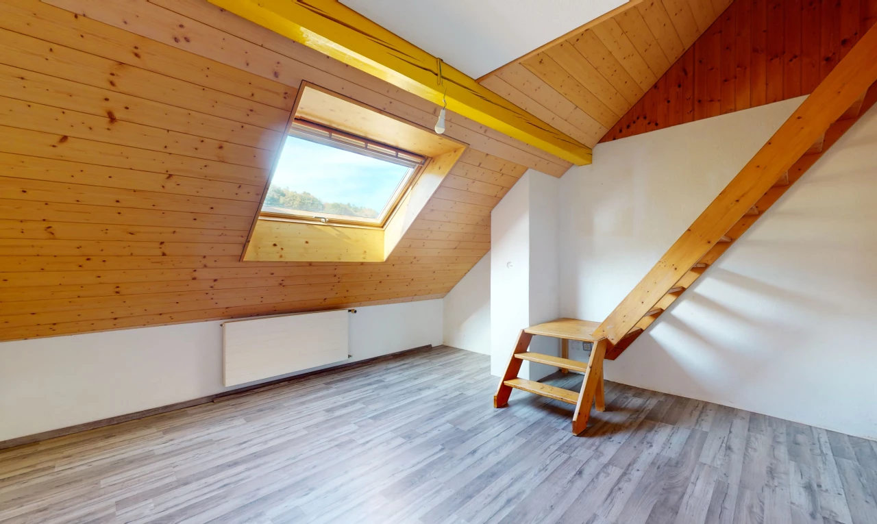 pièce vide avec plancher de bois, plafond voûté, lucarne, mur en bois, et lumière naturelle