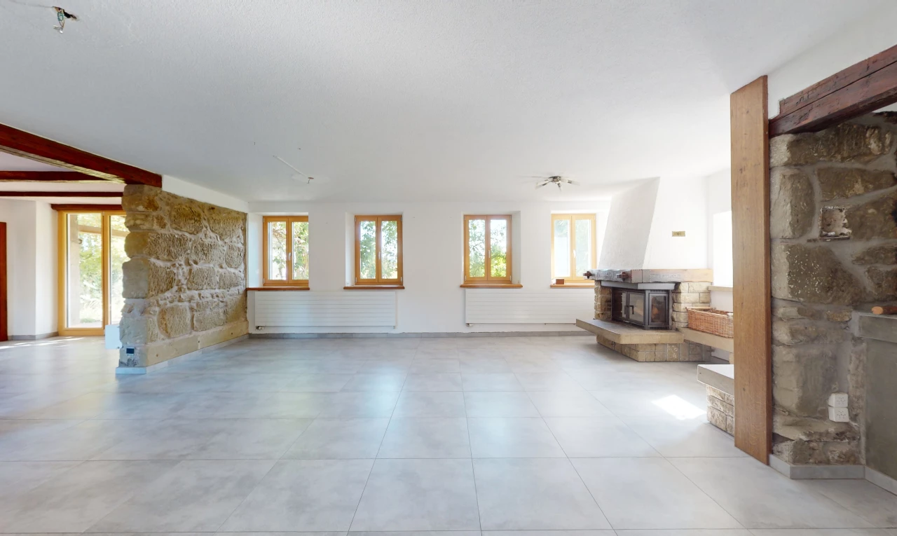 salon avec lumière naturelle, carrelage, poêle à bois, et mur en pierre