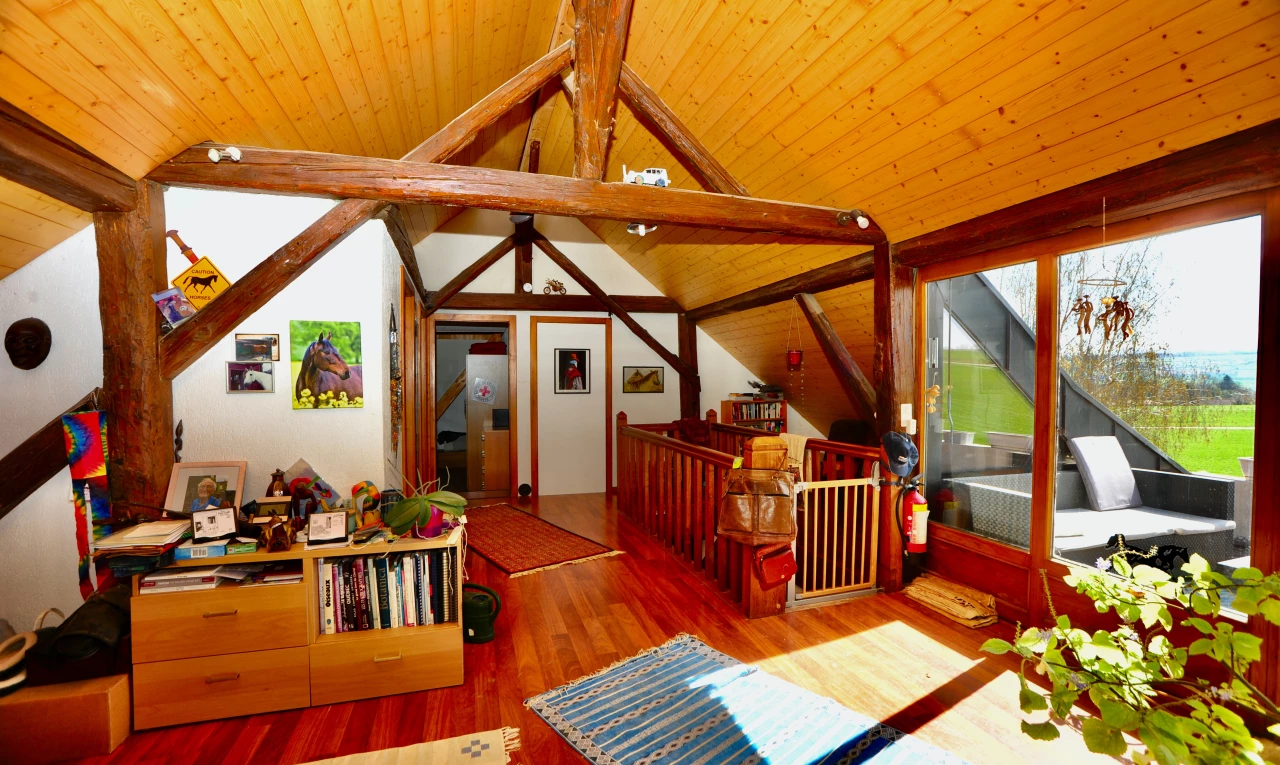 salon avec plancher de bois, plafond voûté, plafond de bois, lumière naturelle, et poutres apparentes