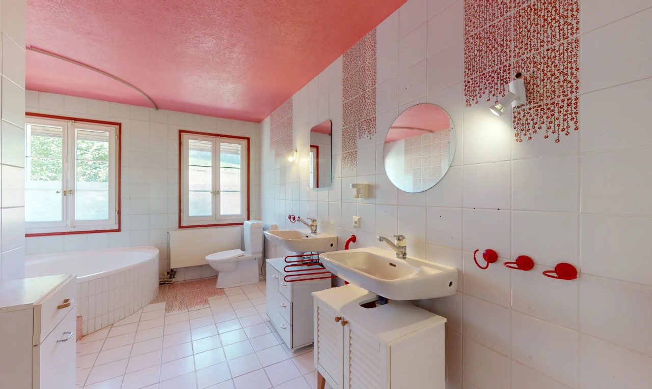 salle de bain avec carrelage, baignoire, miroir, lumière naturelle, et mur carrelé