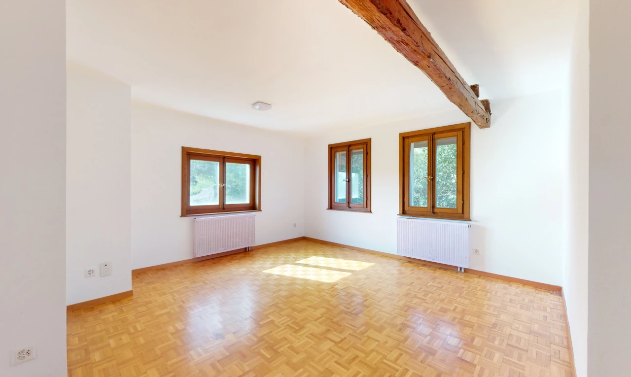 pièce vide avec poutres apparentes, lumière naturelle, radiateur, et parquet