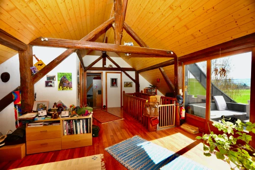 salon avec plancher de bois, plafond voûté, plafond de bois, lumière naturelle, et poutres apparentes