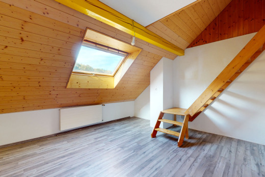 pièce vide avec plancher de bois, plafond voûté, lucarne, mur en bois, et lumière naturelle