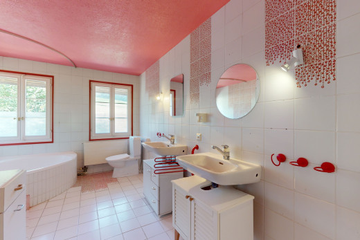 salle de bain avec carrelage, baignoire, miroir, lumière naturelle, et mur carrelé