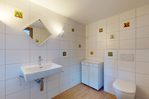 salle de bain avec mur carrelé, miroir, vasque, plancher de bois, et toilettes