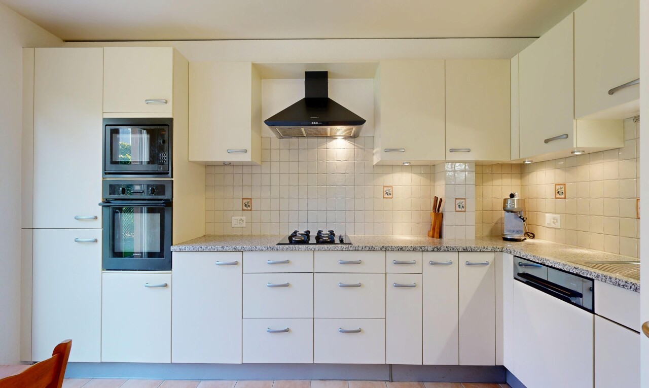cuisine avec light countertops, four, hotte, white cabinets, et armoires blanches