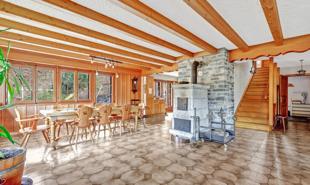 dining area with a wood stove, beam ceiling, and stairs