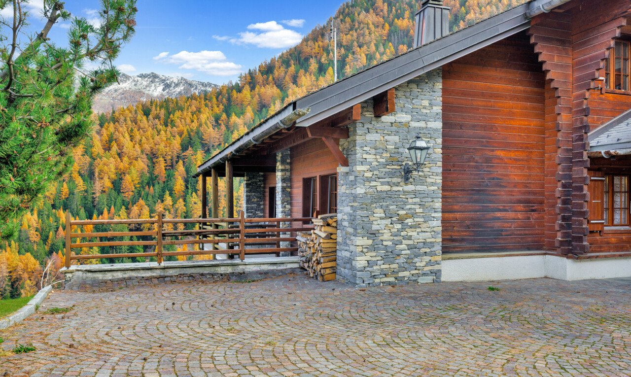 view of home featuring a chimney, a mountain view, stone siding, and a view of trees