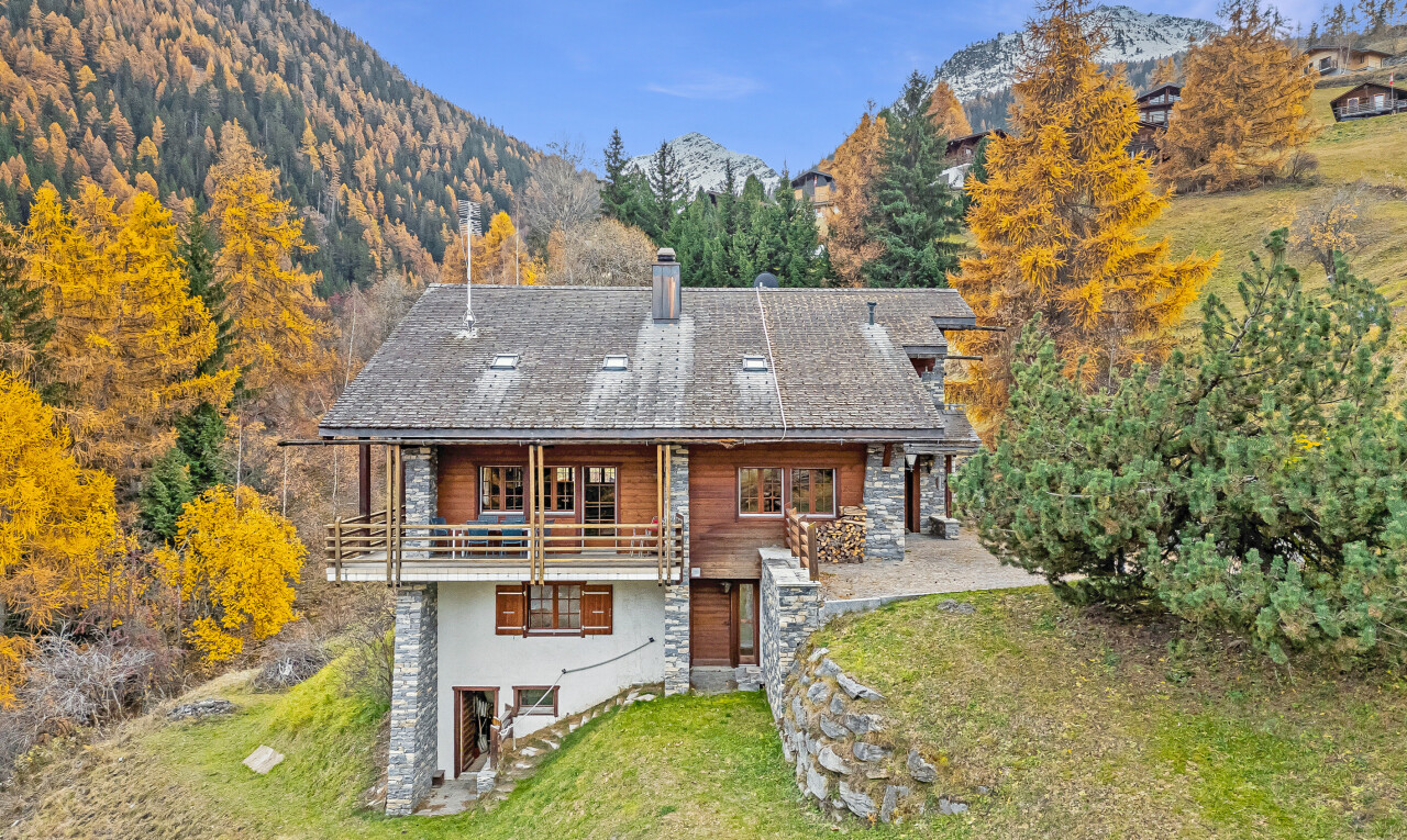 view of home with a yard, a mountain view, a chimney, stone siding, and a patio area
