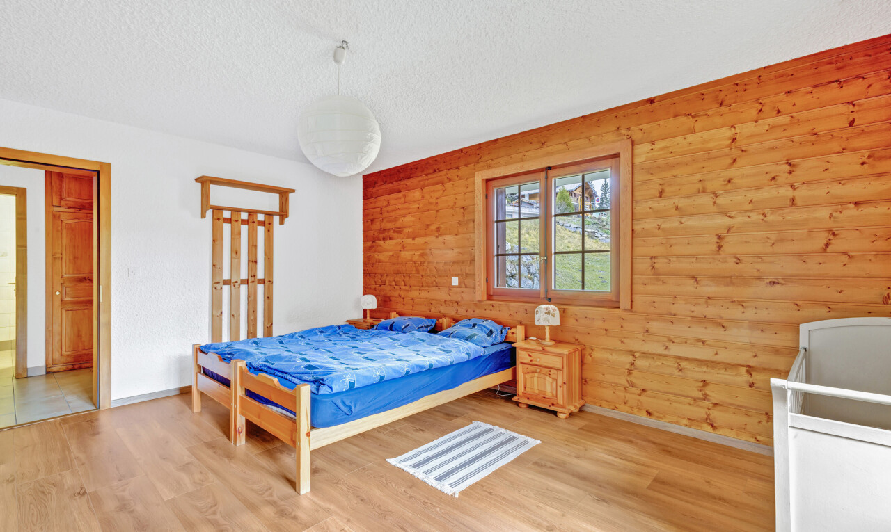 room / bedroom featuring wooden walls, a textured ceiling, and wood finished floors