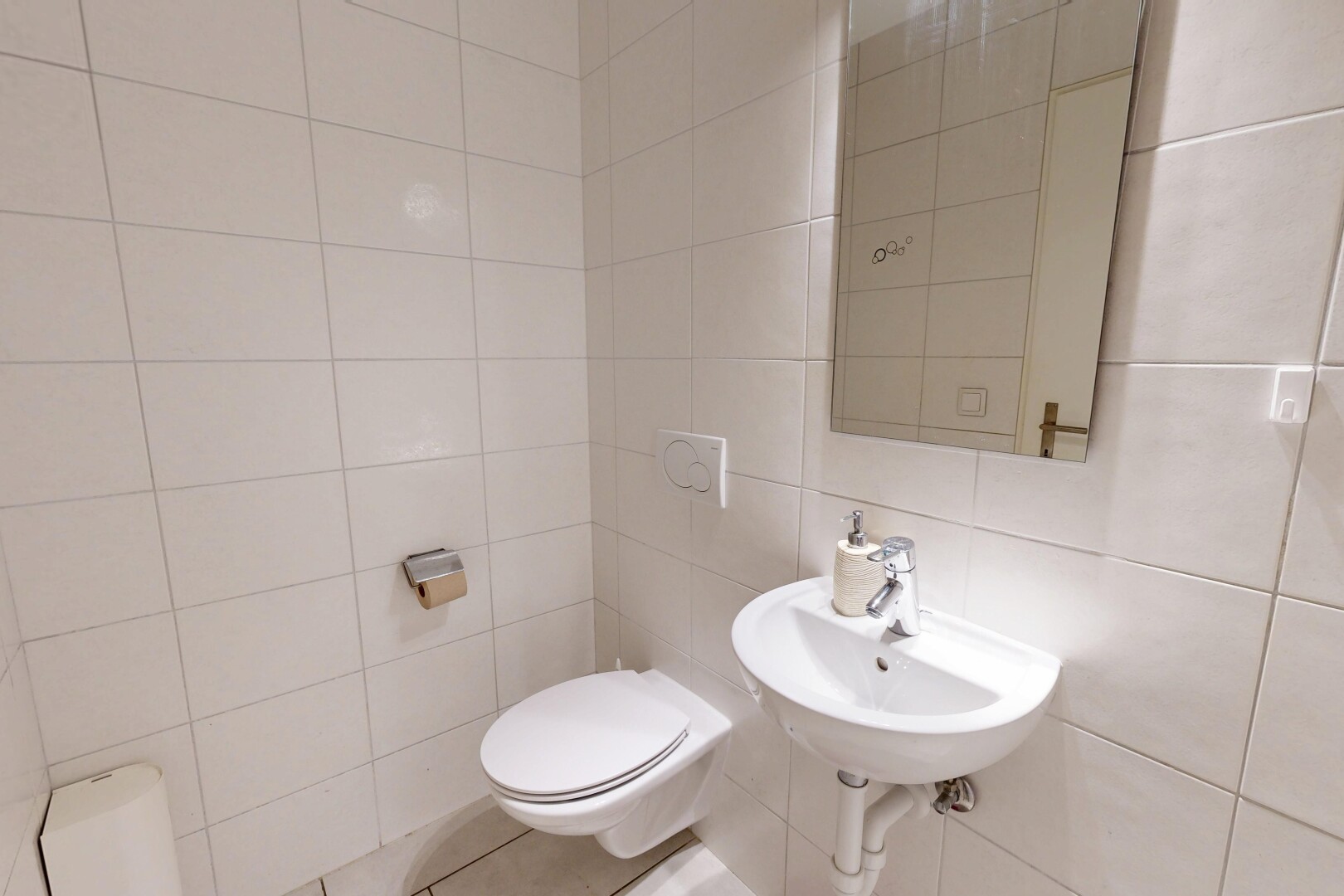 salle de bains avec toilette, mur en carrelage, tile wall, miroir, et évier