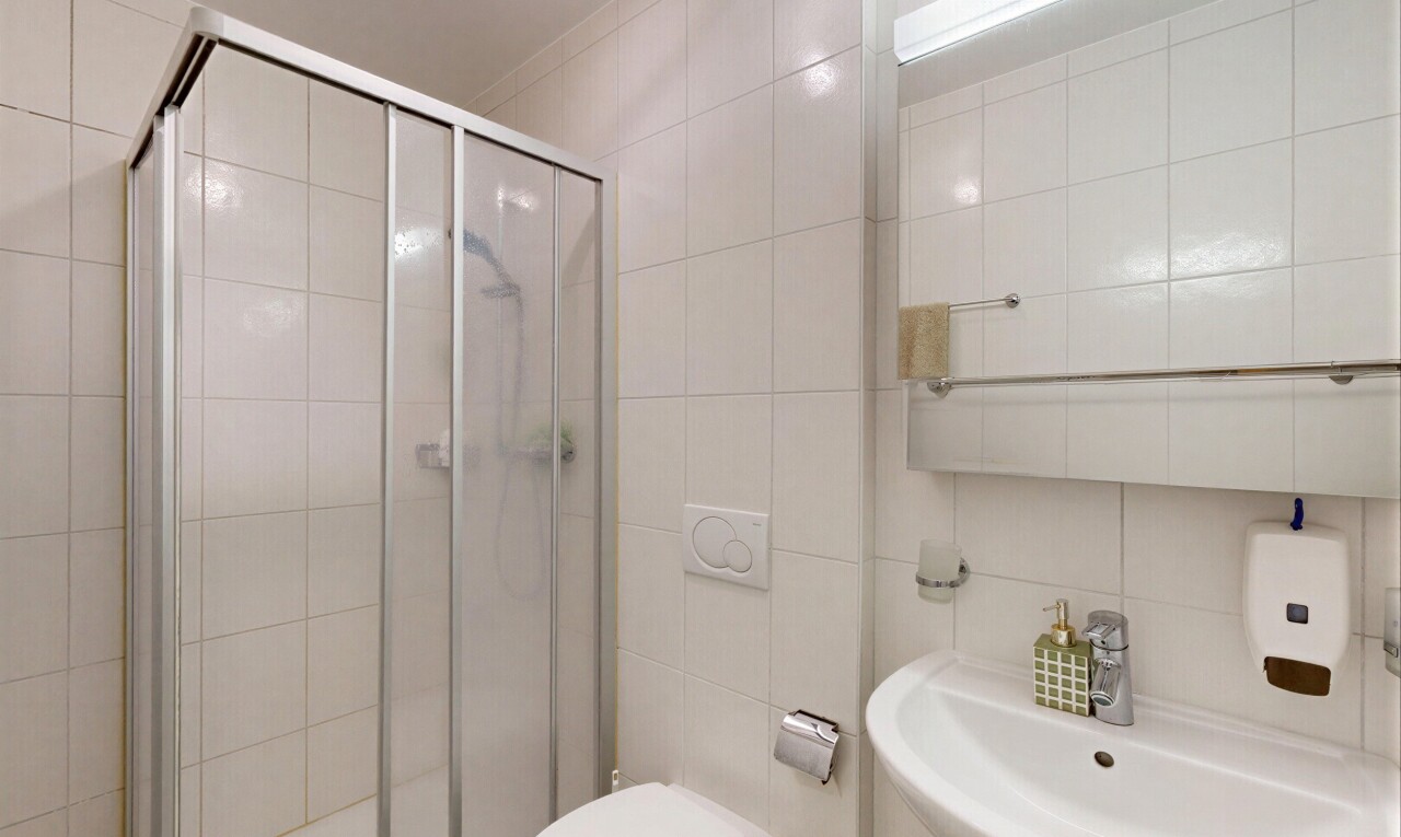 salle de bains avec salle de bain complète, miroir, évier, douche, et tile wall