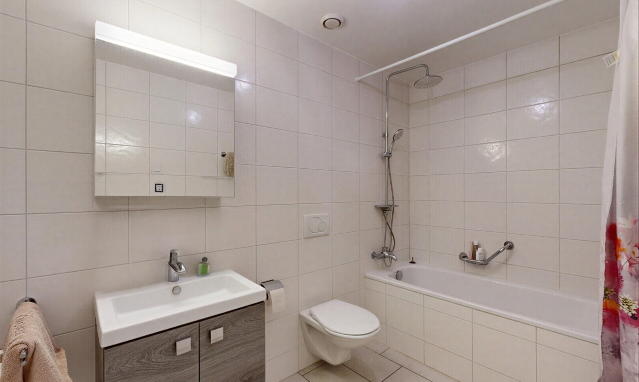 salle de bains avec salle de bain complète, mur en carrelage, tile wall, lavabo (ou coiffeuse selon le contexte), et miroir