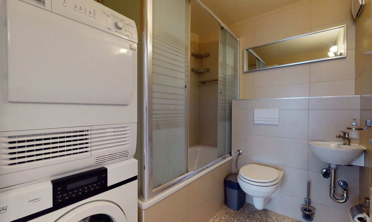 full bathroom with tile walls, stacked washer / dryer, tiled shower / bath, and tile patterned flooring
